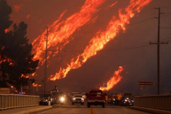 Api membubung di belakang kendaraan saat Kebakaran Hughes membakar di Castaic Lake, California, 22 Januari. REUTERS 