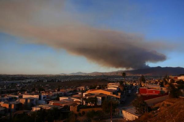 Asap mengepul saat petugas pemadam kebakaran berjuang melawan kebakaran di San Diego, California AS, seperti yang terlihat dari Tijuana, Meksiko 23 Januari 2025. REUTERS 