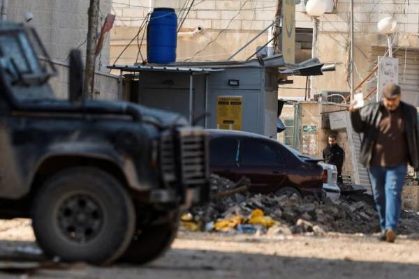 Seorang pria berjalan di samping kendaraan militer Israel, di Jenin, di Tepi Barat yang diduduki Israel, 29 Januari 2025. REUTERS 