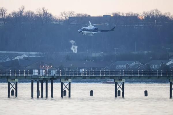 Sebuah helikopter, dalam gambar, terbang di dekat lokasi jatuhnya pesawat American Airlines di Sungai Potomac. (FOTO: GETTY IMAGE) 