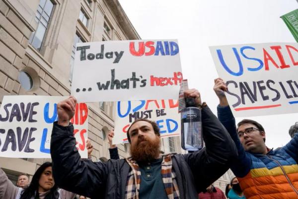 Orang-orang memegang plakat di luar gedung USAID, Elon Musk memimpin upaya perampingan pemerintah federal untuk menutup USAID, di Washington, AS, 3 Februari 2025. REUTERS 