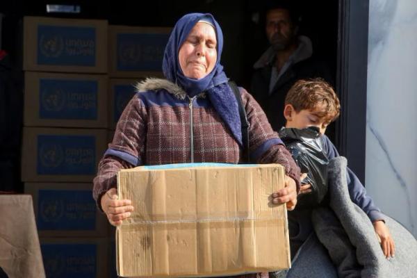 Seorang wanita Palestina membawa kotak bantuan yang diterimanya dari titik distribusi UNRWA, di Khan Younis di Jalur Gaza selatan, 4 Februari 2025. REUTERS 