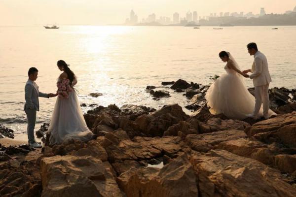 Pasangan mengambil bagian dalam pemotretan pra-pernikahan mereka di tepi laut di Qingdao, provinsi Shandong, Tiongkok, 21 April 2024. REUTERS 