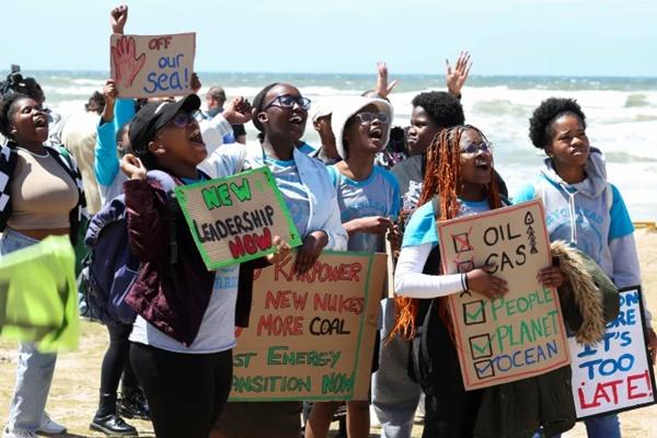 Aktivis iklim memegang plakat saat berdemonstrasi, menyerukan perlawanan keadilan iklim terhadap pengeboran minyak dan gas di lepas pantai Afrika Selatan. (FOTO: REUTERS) 