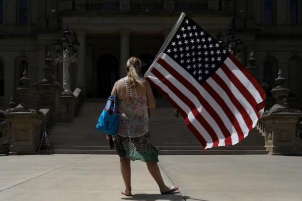 Seorang wanita berdiri dengan bendera Amerika di Lansing, Michigan, AS, 15 Juni 2022. REUTERS 