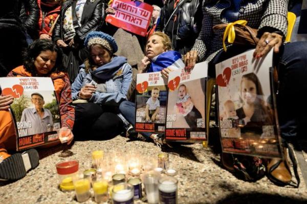 Warga Israel duduk bersama sambil menyalakan lilin dan memegang poster pada hari jenazah sandera diserahkan, di Tel Aviv, Israel 20 Februari 2025. REUTERS 