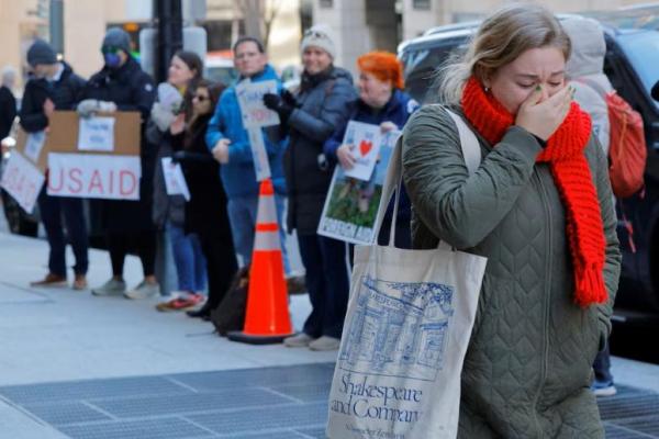 Seorang anggota staf USAID yang baru-baru ini dipecat bereaksi saat meninggalkan kantor, di luar kantor USAID di Washington, AS, 21 Februari 2025. REUTERS 