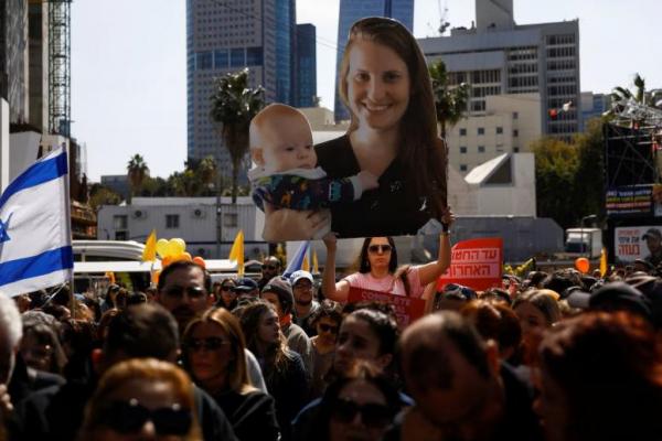 Seorang wanita memegang potongan gambar sandera Shiri Bibas, 32, dengan Kfir Bibas, 9 bulan, di alun-alun umum yang didedikasikan untuk para sandera di Tel Aviv, Israel 26 Februari 2025. REUTERS 