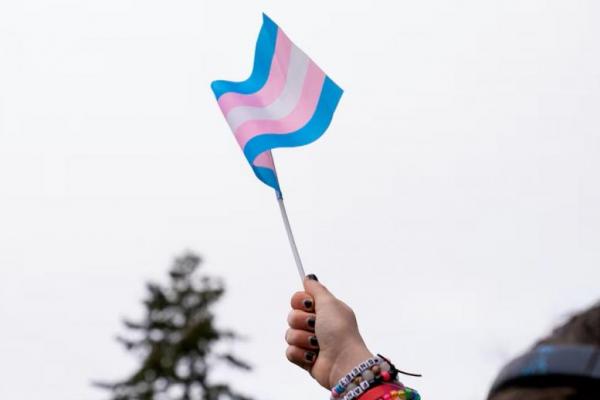 Seorang demonstran memegang bendera trans selama unjuk rasa untuk mendukung kaum muda trans di rumah sakit Anak Seattle di Seattle, Washington, AS, 8 Februari 2025. REUTERS 