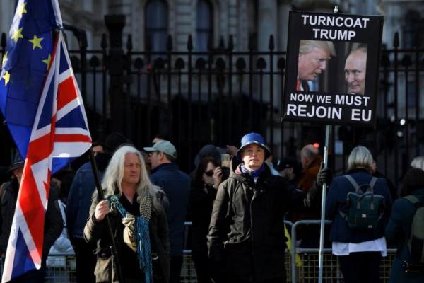 Pengunjuk rasa memegang plakat bergambar Presiden Rusia Vladimir Putin dan Presiden AS Donald Trump di luar Downing Street, London, Inggris, 2 Maret 2025. REUTERS 