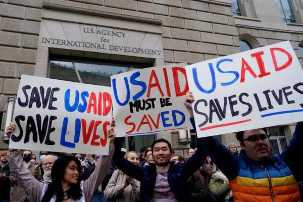 Orang-orang memegang plakat saat gedung USAID ditutup, di Washington, AS, 3 Februari 2025. REUTERS 