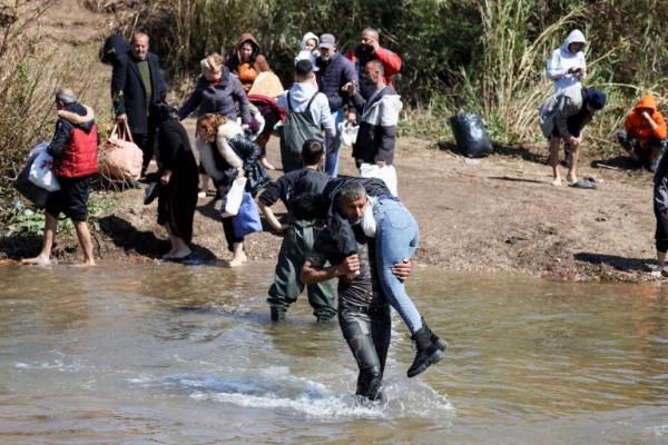 Warga Suriah Alawi, yang melarikan diri dari kekerasan di Suriah barat, berjalan di perairan Nahr El Kabir, Akkar, Lebanon 11 Maret 2025. REUTERS 